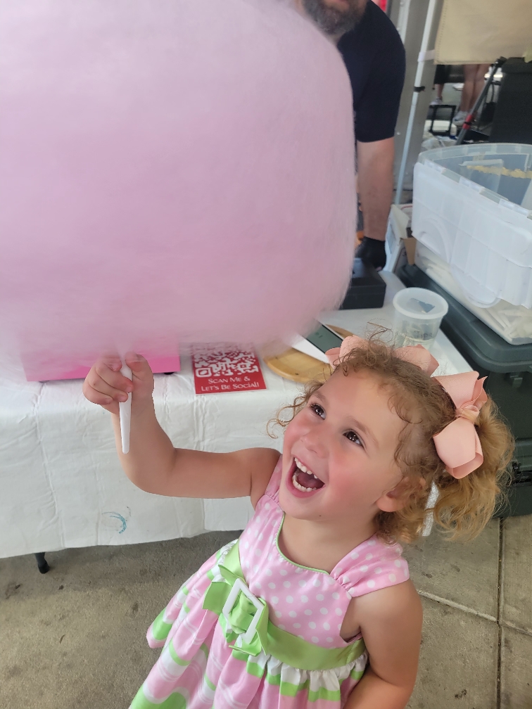 Toddler in a pink dress holding cotton candy