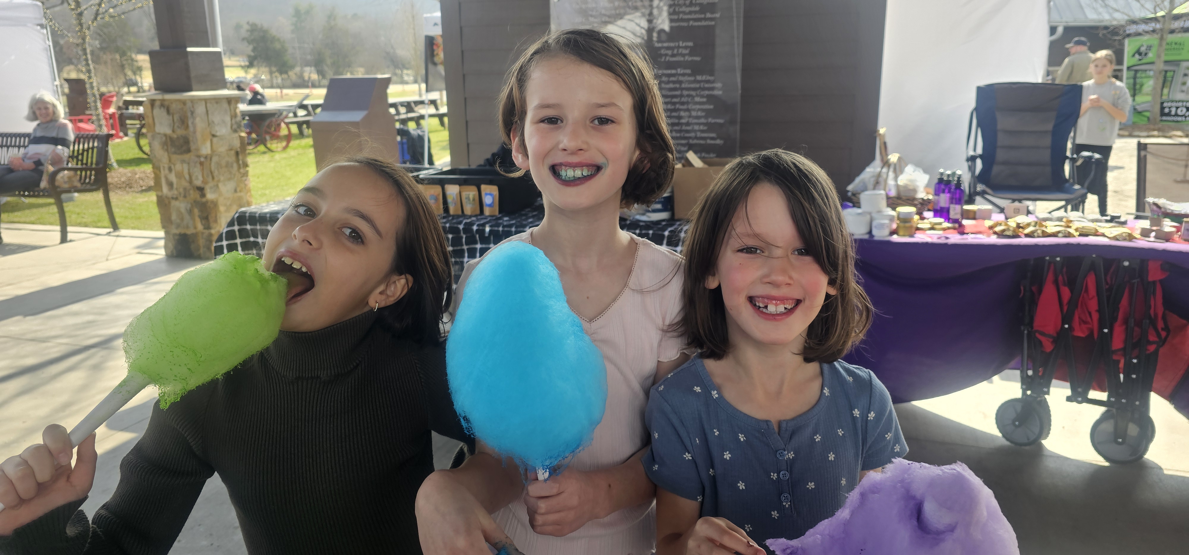Three kids eating green, blue, and purple cotton candy