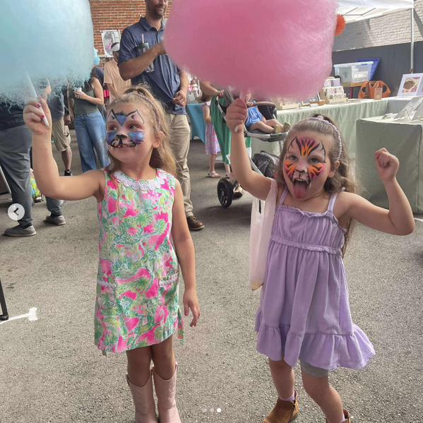 Two girls with cat and tiger face paint holding cotton candy