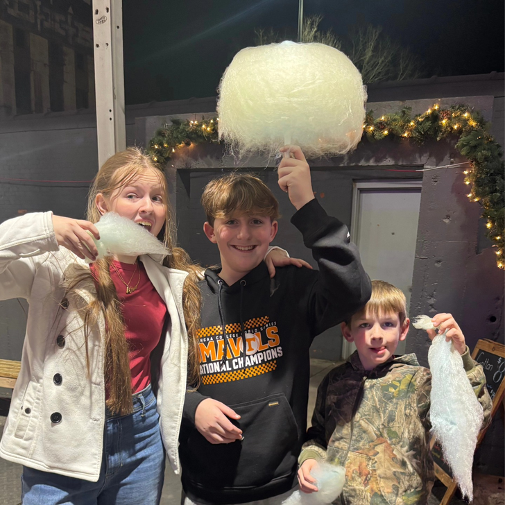 Three friends with cotton candy at a winter evening event